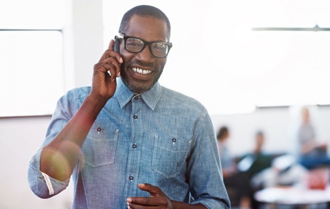 A man smiles while talking on his phone.